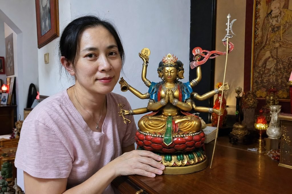 Doumu Yuanjun Taoist statue supported by a Malaysian Chinese woman in a home altar setting