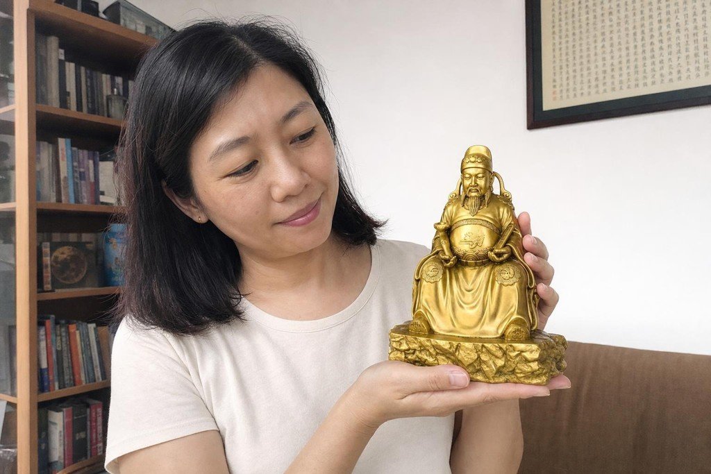 Wenchang Dijun statue held by a Malaysian Chinese woman in a home study setting